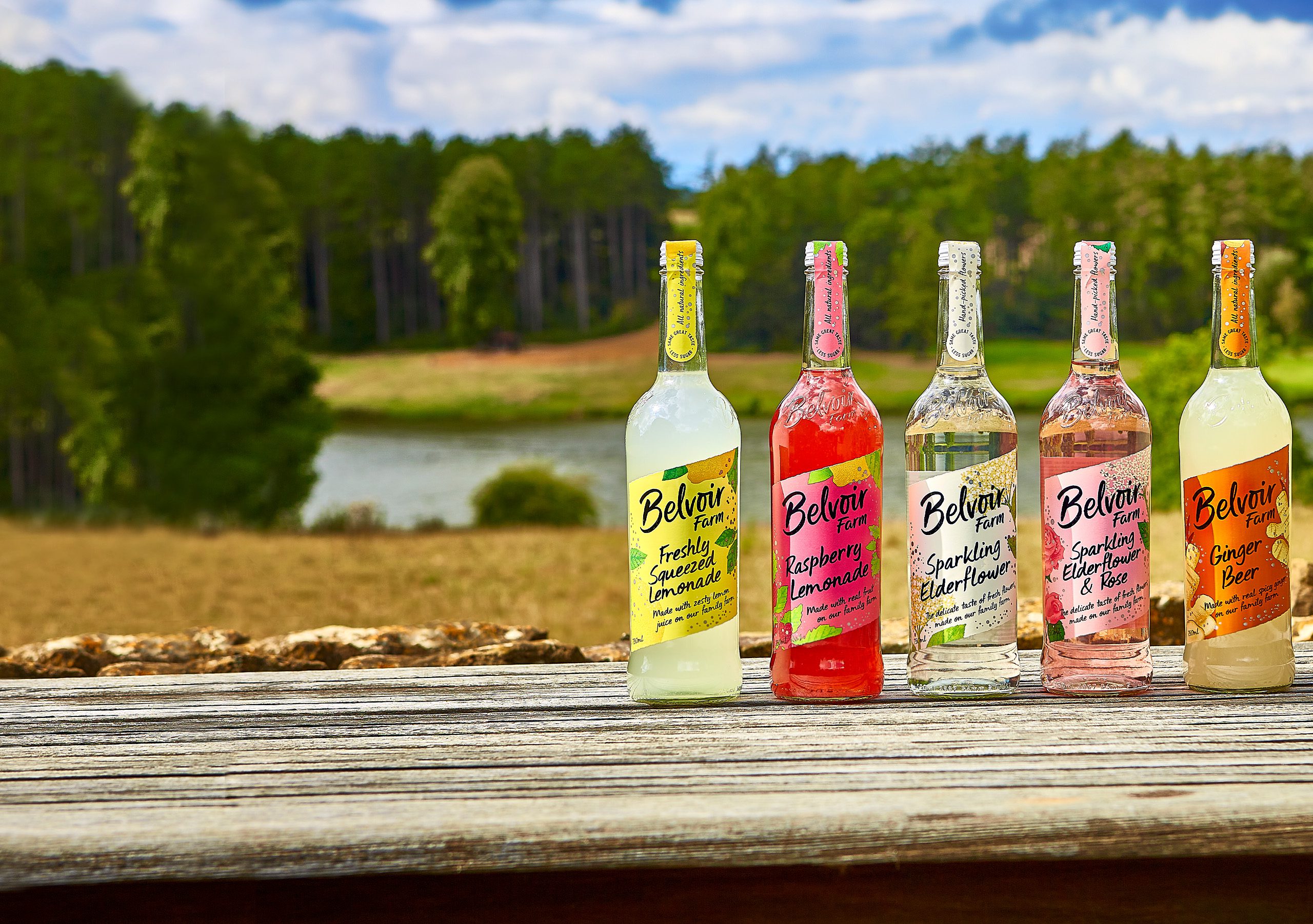 A range of Belvoir Farm sparkling drinks and cordials against a natural landscape